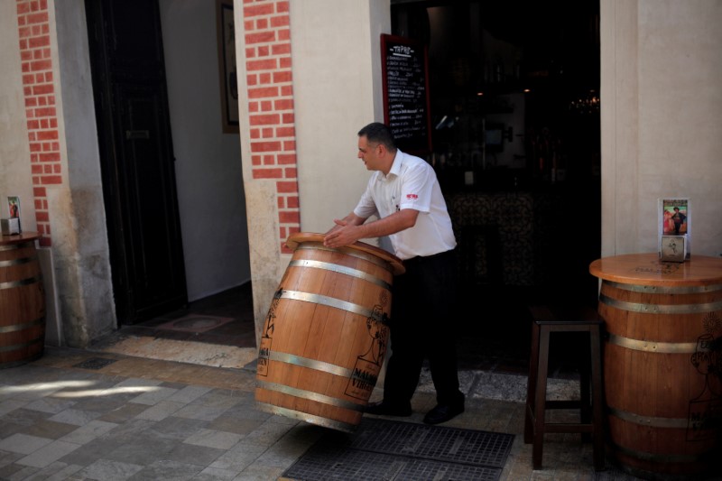 © Reuters. FILE PHOTO: A waiter places a barrel table at the terrace of a restaurant in downtown Malaga