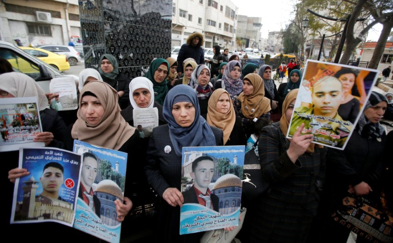 © Reuters. The mother of Palestinian assailant Abdel Fattah al-Sharif holds his poster during a protest in the West Bank city of Hebron