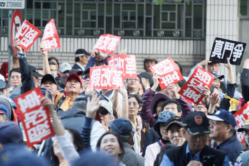 © Reuters. Demonstrators hold placards that reads "False reform" during a protest against the reforming of Taiwan's deficit-ridden pension programs, in Taipei, Taiwan