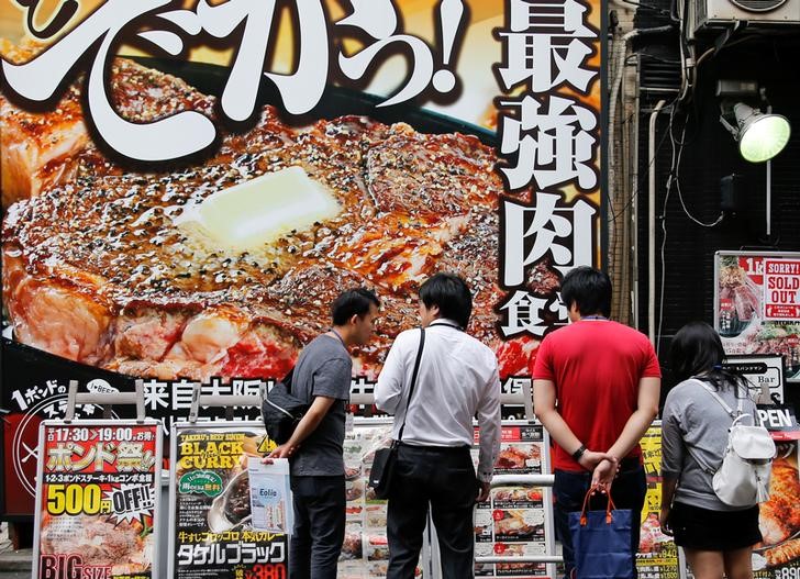 © Reuters. People look at advertisements of restaurants in Tokyo