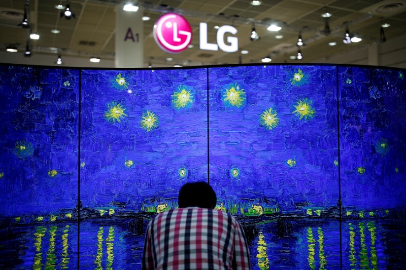 © Reuters. FILE PHOTO: A man examines LG Electronics' double-faced and curved OLED TV during Korea Electronics Show 2016 in Seoul, South Korea