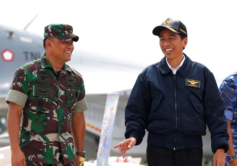 © Reuters. Indonesia's President Joko Widodo talks with military chief Gatot Nurmantyo as walk past fighter jets and weapons during a military exercise on Natuna Island