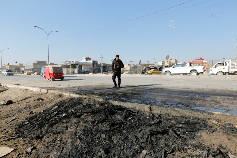 © Reuters. A member of Iraqi security forces stands at the site of car bomb attack in the predominately Shi'ite Muslim neighbourhood of al-Obaidi