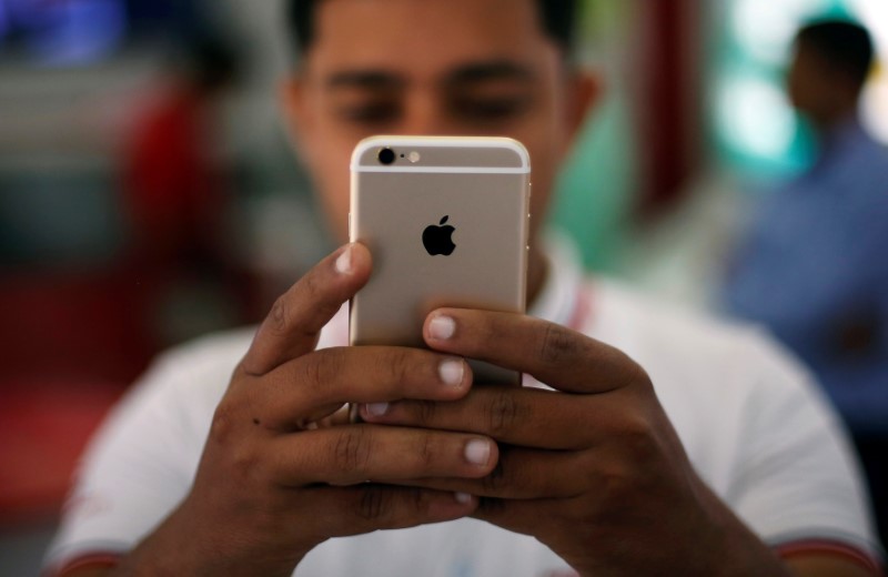 © Reuters. A salesman checks a customer's iPhone at a mobile phone store in New Delhi