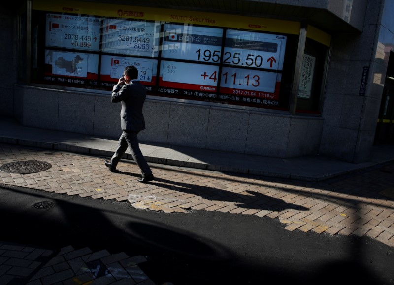 © Reuters. A man walks past an electronic board showing stock prices outside a brokerage in Tokyo