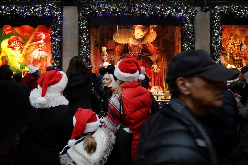 © Reuters. People wearing Christmas hats look in a shop window on Fifth Avenue during a busy shopping day in Manhattan