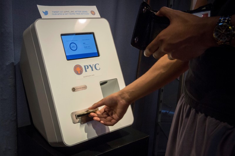 © Reuters. A customer feeds cash currency in to a Bitcoin ATM located in Flat 128, a boutique in New York's West Village