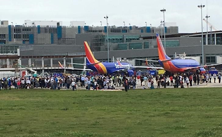 © Reuters. Viajeros son evacuados de la terminal hacia la pista tras el tiroteo en el aeropuerto internacional Fort Lauderdale-Hollywood, en Estados Unidos