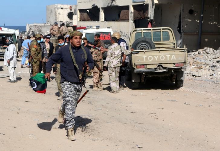 © Reuters. Fighter of Libyan forces allied with the U.N.-backed government runs as forces clear Ghiza Bahriya, the final district of the former Islamic State stronghold of Sirte