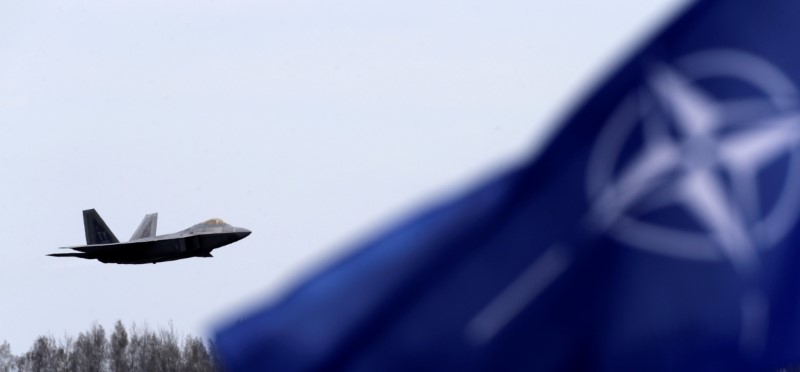 © Reuters. NATO flag flutters as U.S. Air Force F-22 Raptor fighter flies over the military air base in Siauliai