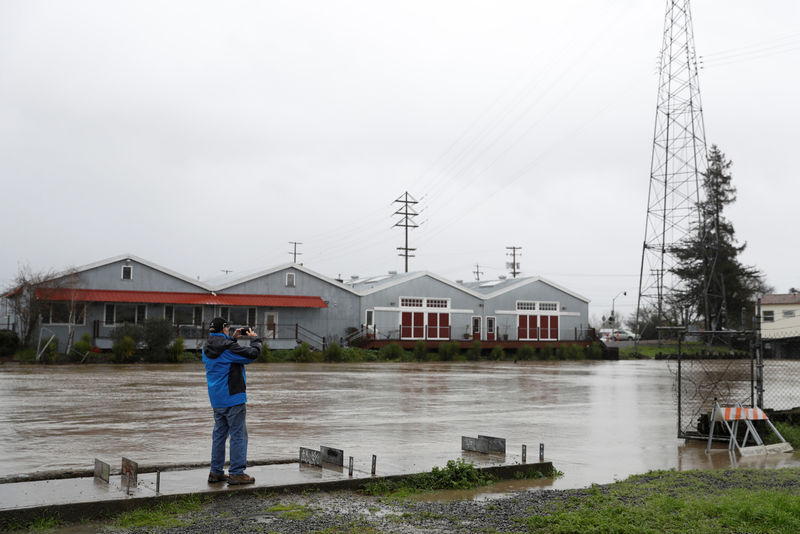 © Reuters. A man takes a photograph of a rising Petaluma River during a winter storm in Petaluma