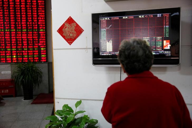 © Reuters. Инвестор смотрит на табло с информацией о торгах в брокерской компании Шанхая