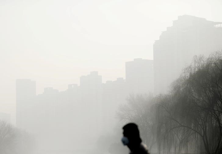 © Reuters. Pessoa usa máscara em dia de neblina forte em Pequim