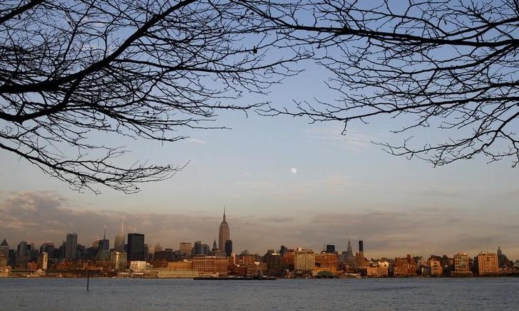 © Reuters. The moon rises behind the  Empire State Building and the skyline of Manhattan at sunset in New York