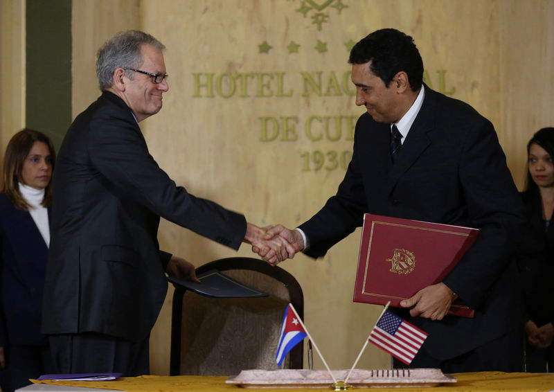 © Reuters. DeLaurentis, U.S. Charge d'Affaires in Cuba, shakes hands with Cuban Deputy Transportation Minister Rodriguez Davila after signing accords in Havana