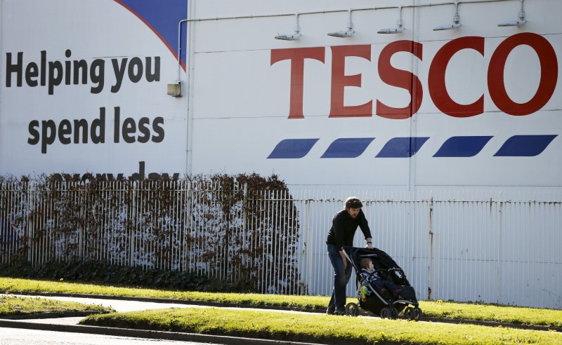 © Reuters. A man pushes a pram past a Tesco supermarket near Altrincham, northern England
