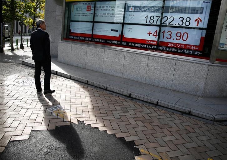 © Reuters. A man looks at an electronic board showing Japan's Nikkei average outside a brokerage in Tokyo