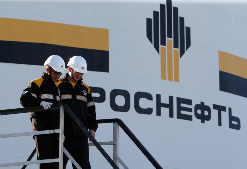 © Reuters. Workers stand next to logo of Russia's Rosneft oil company at central processing facility of Rosneft-owned Priobskoye oil field outside Nefteyugansk