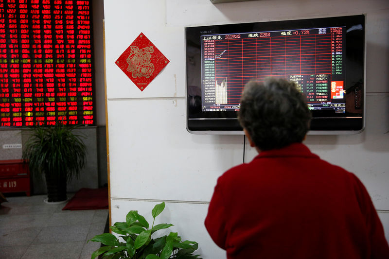 © Reuters. An investor looks at an electronic board showing stock information on the first trading day after the New Year holiday at a brokerage house in Shanghai