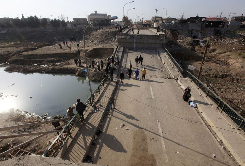 © Reuters. Displaced people cross the bridge in Al-Muthanna neighborhood of Mosul