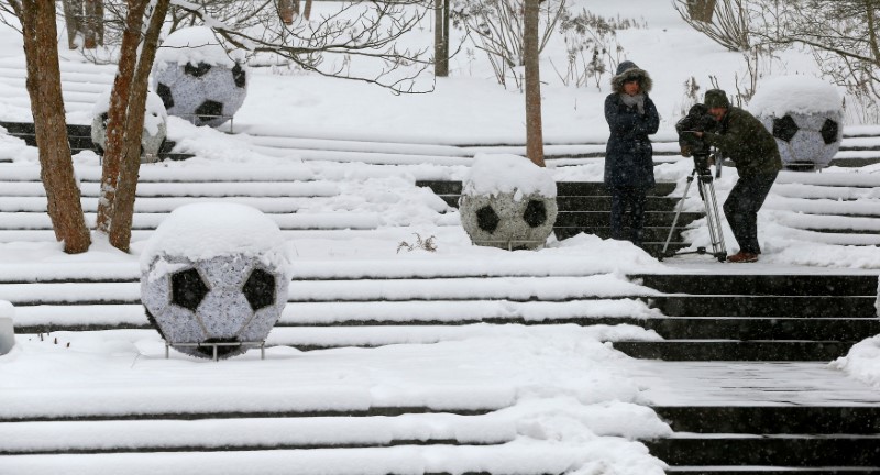 © Reuters. A cameraman takes pictures during a snowfall in front of the FIFA headquarters in Zurich