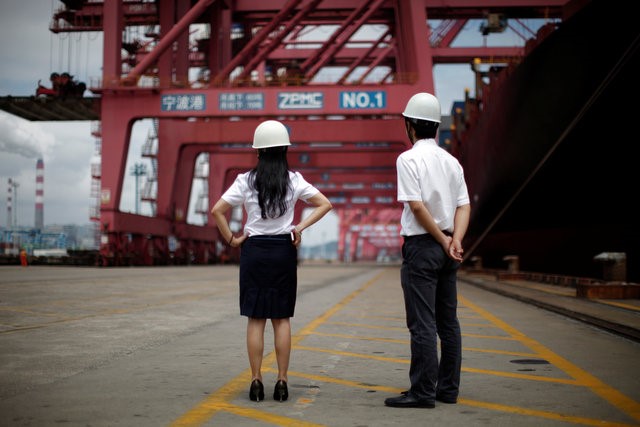 © Reuters. Employees stand next to a container ship at Ningbo port in Ningbo