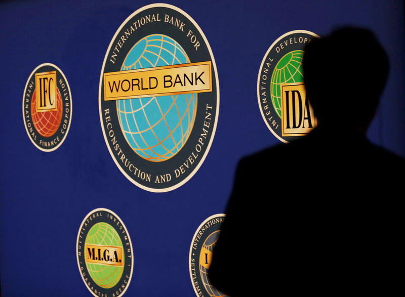 © Reuters. FILE PHOTO: Man is silhouetted against logo of World Bank at main venue for IMF and World Bank annual meeting in Tokyo