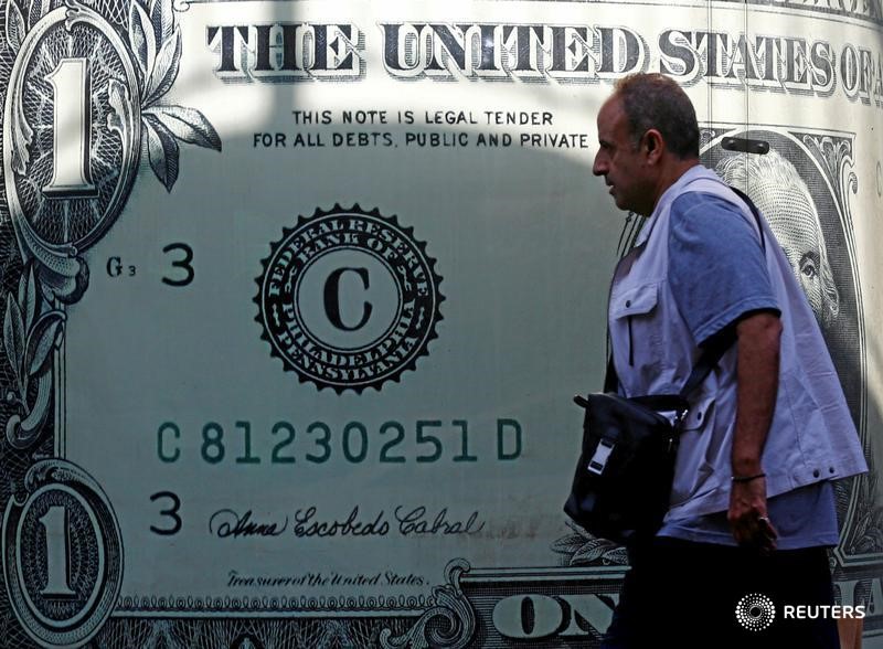 © Reuters. Мужчина проходит мимо изображения американской валюты в Каире