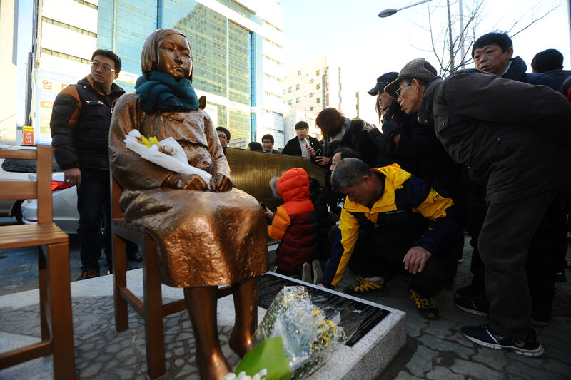 © Reuters. A flower is laid on a statue of a girl that represents the sexual victims by the Japanese military during a rally in front of Japanese Consulate in Busan