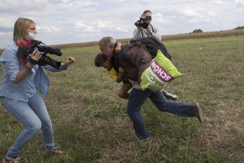 © Reuters. FILE PHOTO: A migrant runs with a child before tripping on TV camerawoman Petra Laszlo and falling as he tries to escape from a collection point in Roszke village, Hungary