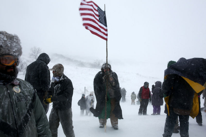 © Reuters. A man holds an American flag while protesting near Standing Rock Indian Reservation, North Dakota