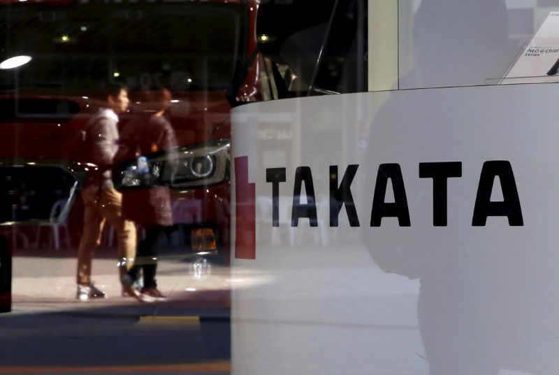 © Reuters. A logo of Takata Corp is seen with its display as people are reflected in a window at a showroom for vehicles in Tokyo