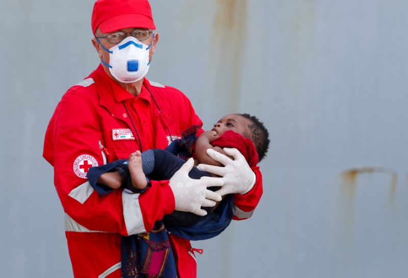 © Reuters. A member of the Italian Red Cross holds a child after disembarking from the Italian Navy vessel Aviere in the Sicilian harbour of Augusta