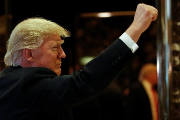 © Reuters. U.S.President-elect Donald Trump gestures to people in the lobby after speaking to the news media with television personality Steve Harvey and businessman Greg Calhoun after their meeting at Trump Tower in New YorkYork,