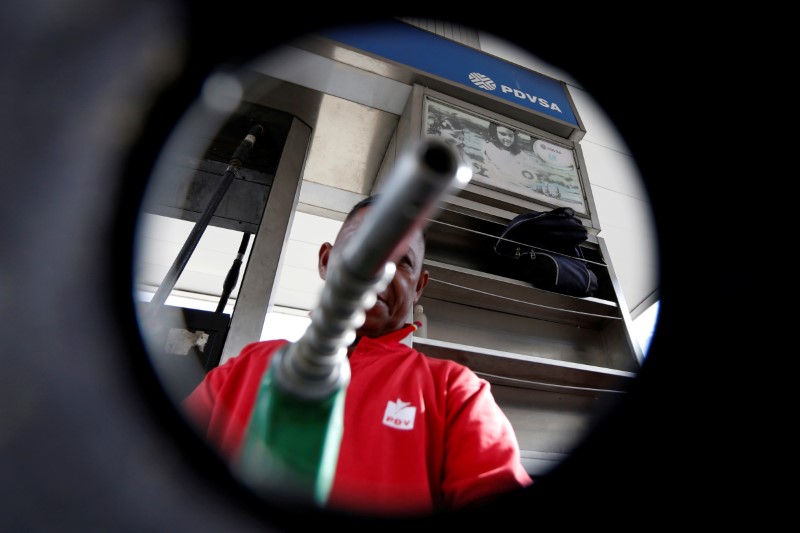 © Reuters. FILE PHOTO:  A man points a fuel nozzle at the camera for a photograph at a gas station belonging to Venezuelan state oil company PDVSA in Caracas