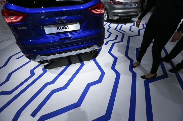 © Reuters. Visitors walk along a Ford Kuga car during the media day at the Frankfurt Motor Show (IAA) in Frankfurt