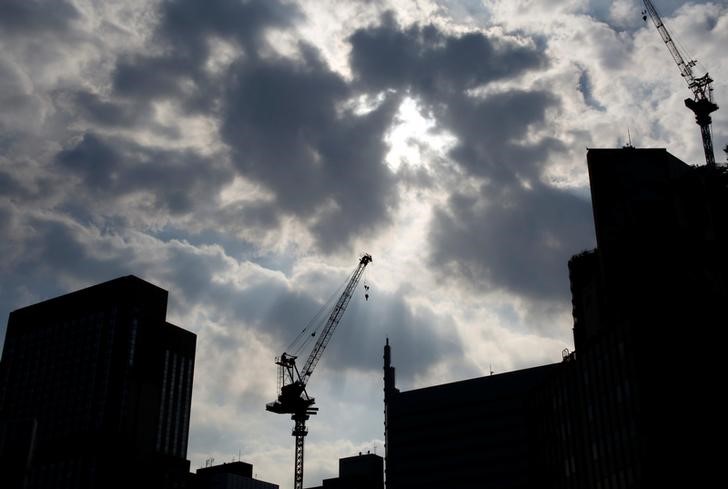 © Reuters. Cranes at a construction site are silhouetted at a commercial area in Tokyo