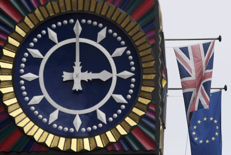 © Reuters. The British Union flag and the European Union flag are seen flying behind a clock in the City of London, Britain