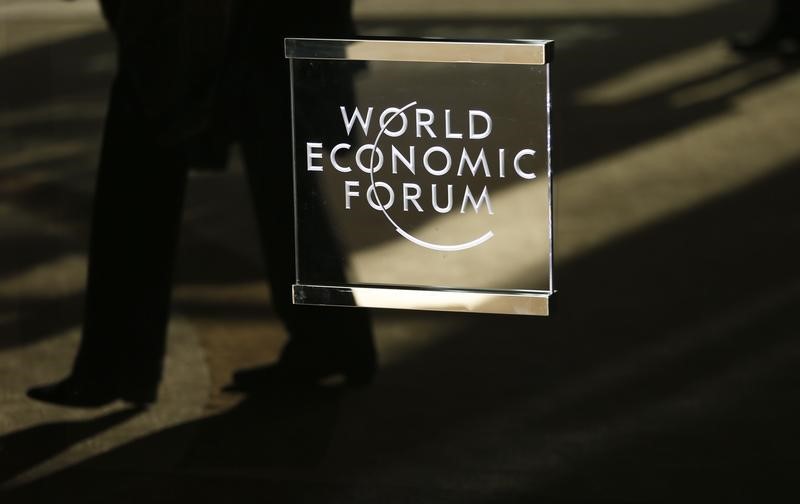 © Reuters. A man walks past the official logo of the World Economic Forum (WEF) in Davos