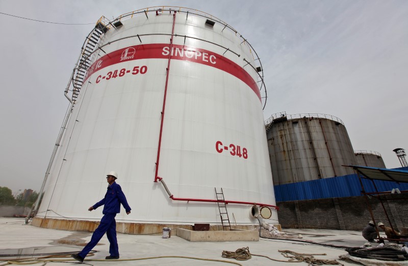 © Reuters. File photo of an employee walking past oil tanks at a Sinopec refinery in Wuhan, Hubei province