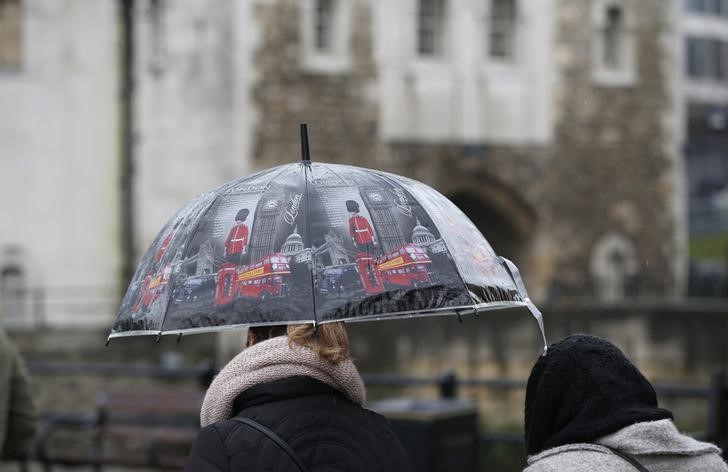 © Reuters. A tourist carrying an umbrella walks in the rain during a spell of wet weather next to The Tower of London, in London