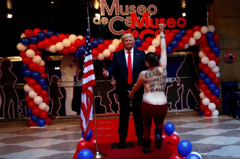 © Reuters. A topless FEMEN activist runs to grab the crotch of a life-sized wax statue of U.S. President-elect Trump during an unveiling ceremony at Madrid's wax museum