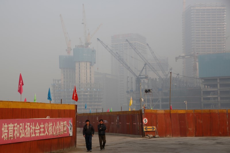 © Reuters. Men walk outside at a construction site in Beijing