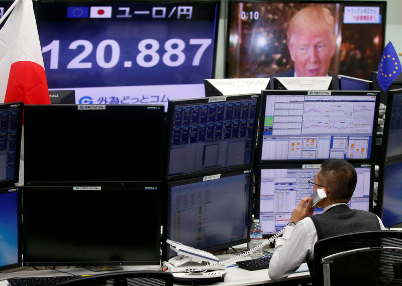© Reuters. Employee of a foreign exchange trading company works near monitors showing U.S. President-elect Donald Trump, and the Japanese yen's exchange rate against the euro in Tokyo