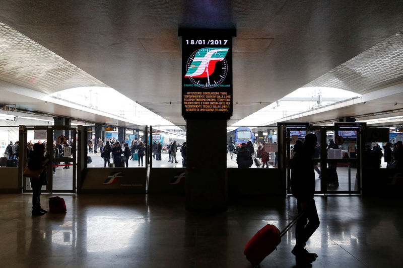 © Reuters. Commuters stands at Termini central train station as a billboard advises that some trains will be disrupted following an earthquake in Rome