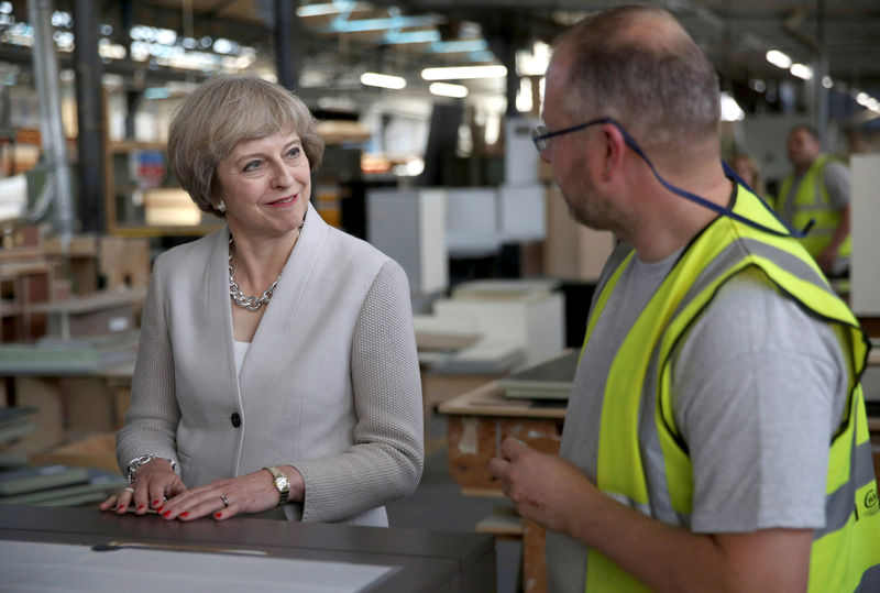 © Reuters. FILE PHOTO: Britain's Prime Minister Theresa May speaks with a worker as she visits a joinery factory in London