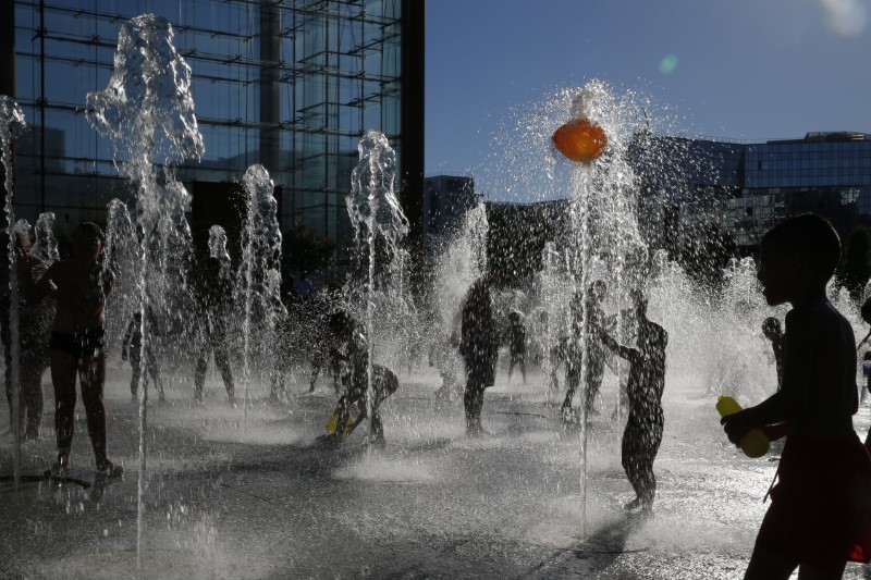 © Reuters. People cool off in fountains as hot summer temperatures hit Paris