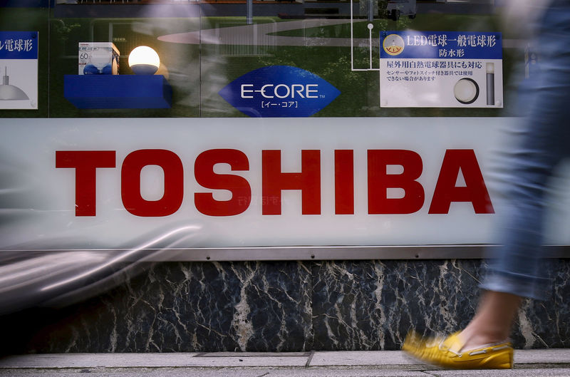 © Reuters. FILE PHOTO:Pedestrians walk past a logo of Toshiba Corp outside an electronics retailer in Tokyo