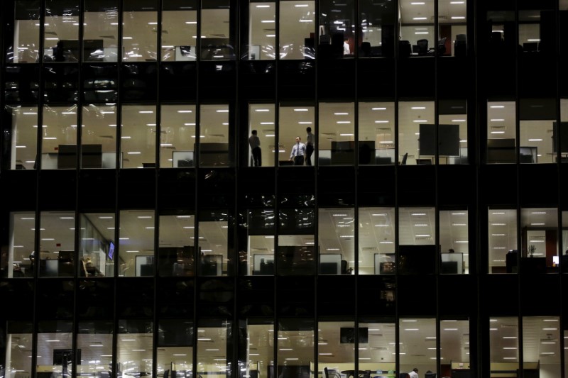© Reuters. Workers are seen in office windows in the financial district of Canary Wharf in London
