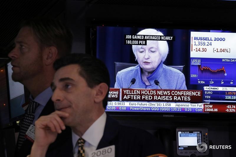 © Reuters. A trader works on the floor of the New York Stock Exchange as a television screen displays coverage of U.S. Federal Reserve Chairman Janet Yellen shortly after the announcement that the U.S. Federal Reserve will hike interest rates, in New York